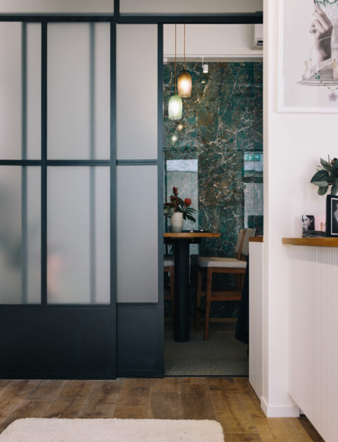 Interior view of Alice Herald in Wanaka, featuring a modern sliding glass door, wooden flooring, and a warmly lit seating area with contemporary décor.