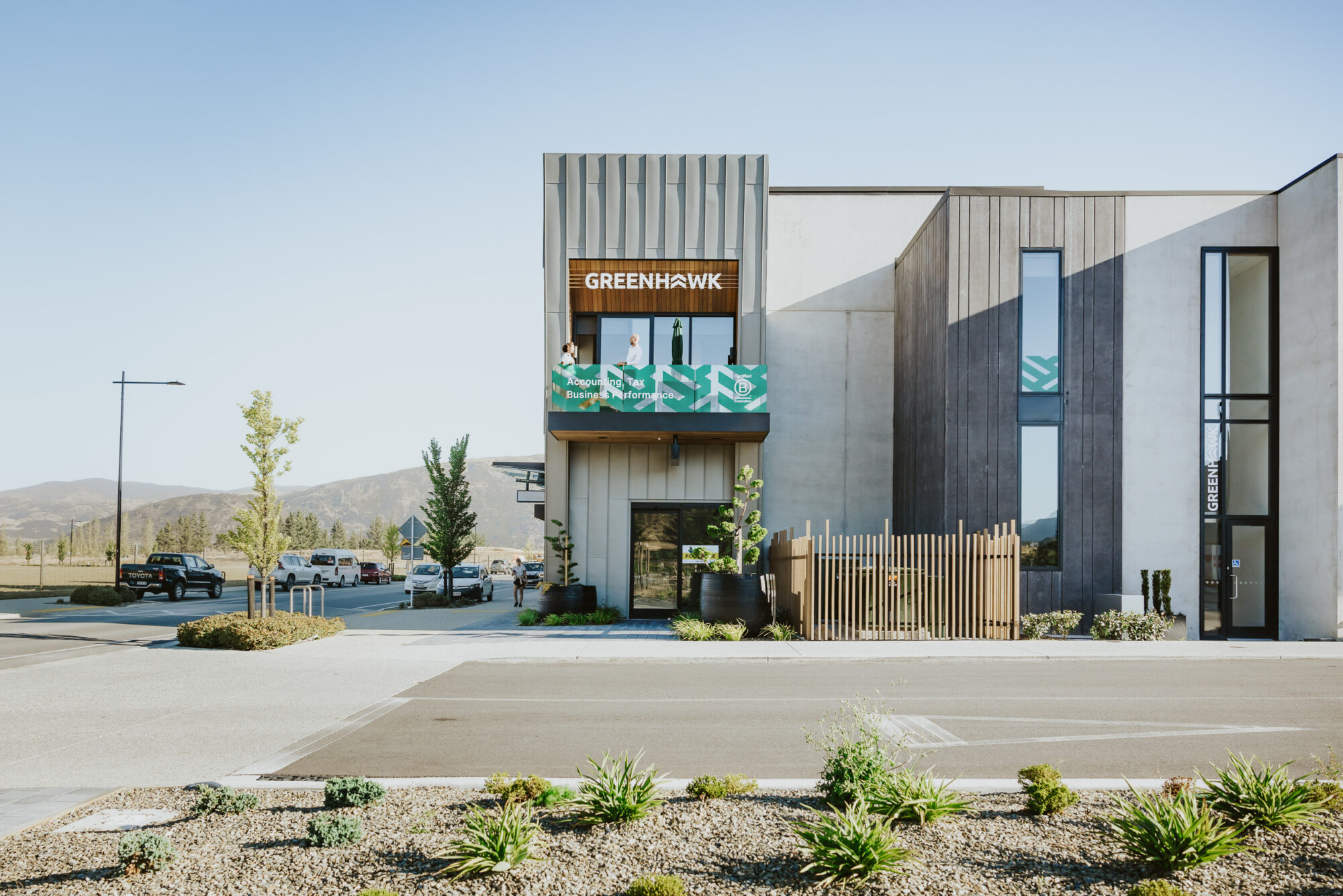 Green Hawk Accounting office in Wānaka—a modern, minimalist building with a wooden sign, balcony, and mountain views