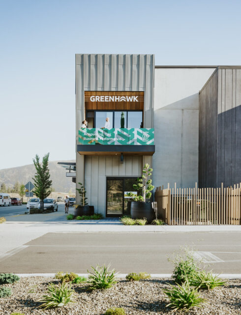 Green Hawk Accounting office in Wānaka—a modern, minimalist building with a wooden sign, balcony, and mountain views