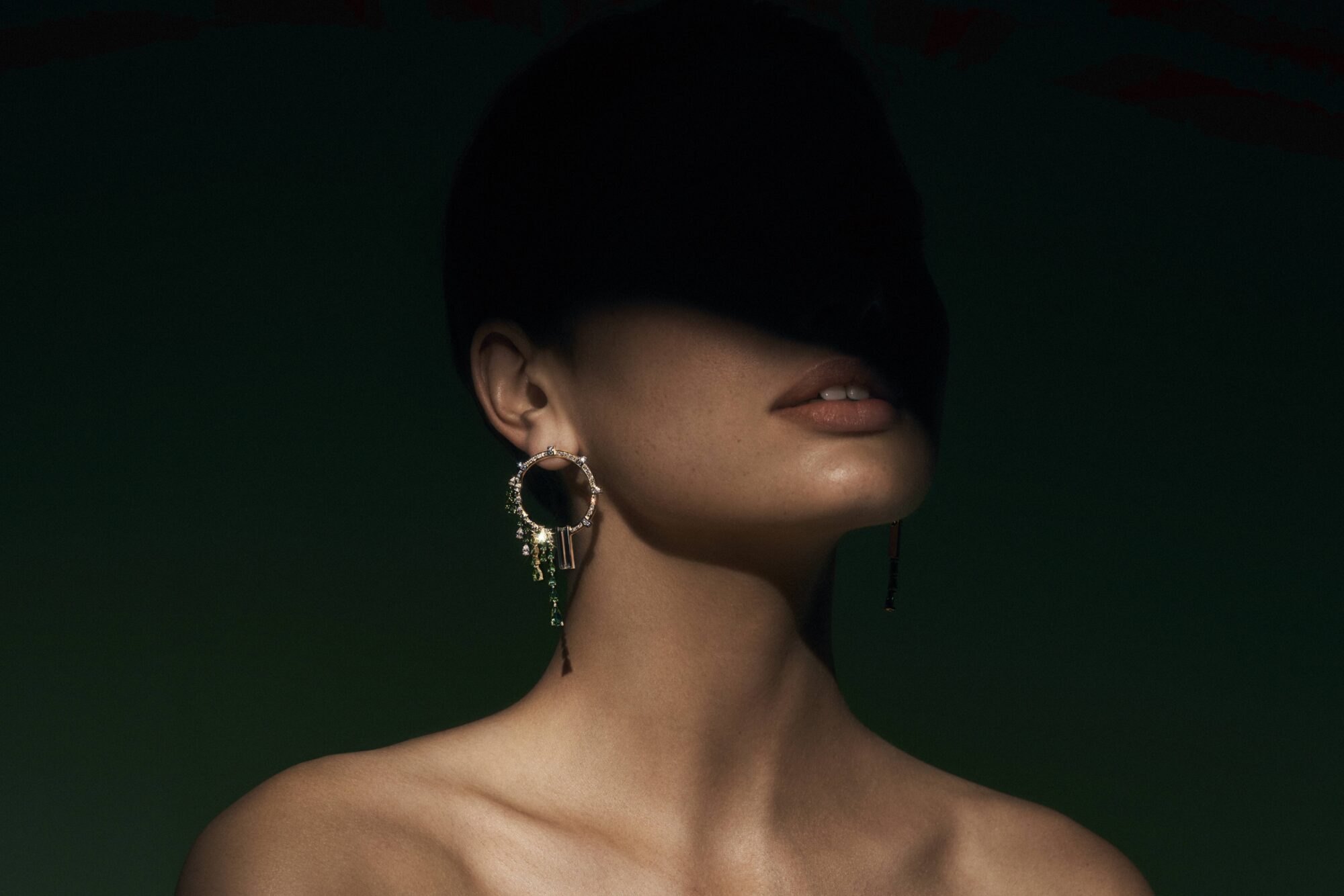 Statement earring by Alice Herald Wānaka displayed on a model against a dark green background, with elegant pendant design hanging from circular stud.