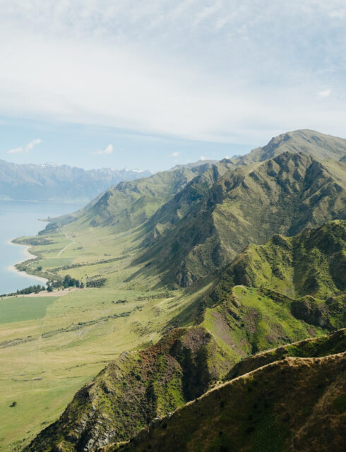View of Lake Hawea and surrounding green mountains from the top of the Sawyer Burn Track.